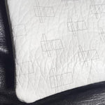 Load image into Gallery viewer, A close-up of a white textured leather or faux-leather cushion with a subtle geometric line pattern, resting on a black leather surface.