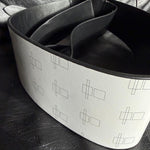 Load image into Gallery viewer, A wide white belt with a black interior and a repeating geometric line pattern, photographed on a dark textured surface.