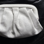 Load image into Gallery viewer, A white textured leather clutch purse with a pleated design and a curved top handle, shown against a solid black background.