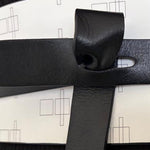 Load image into Gallery viewer, A close-up of a black and white belt with a featuring a minimalist black geometric line pattern, styled over a black ribbed top.
